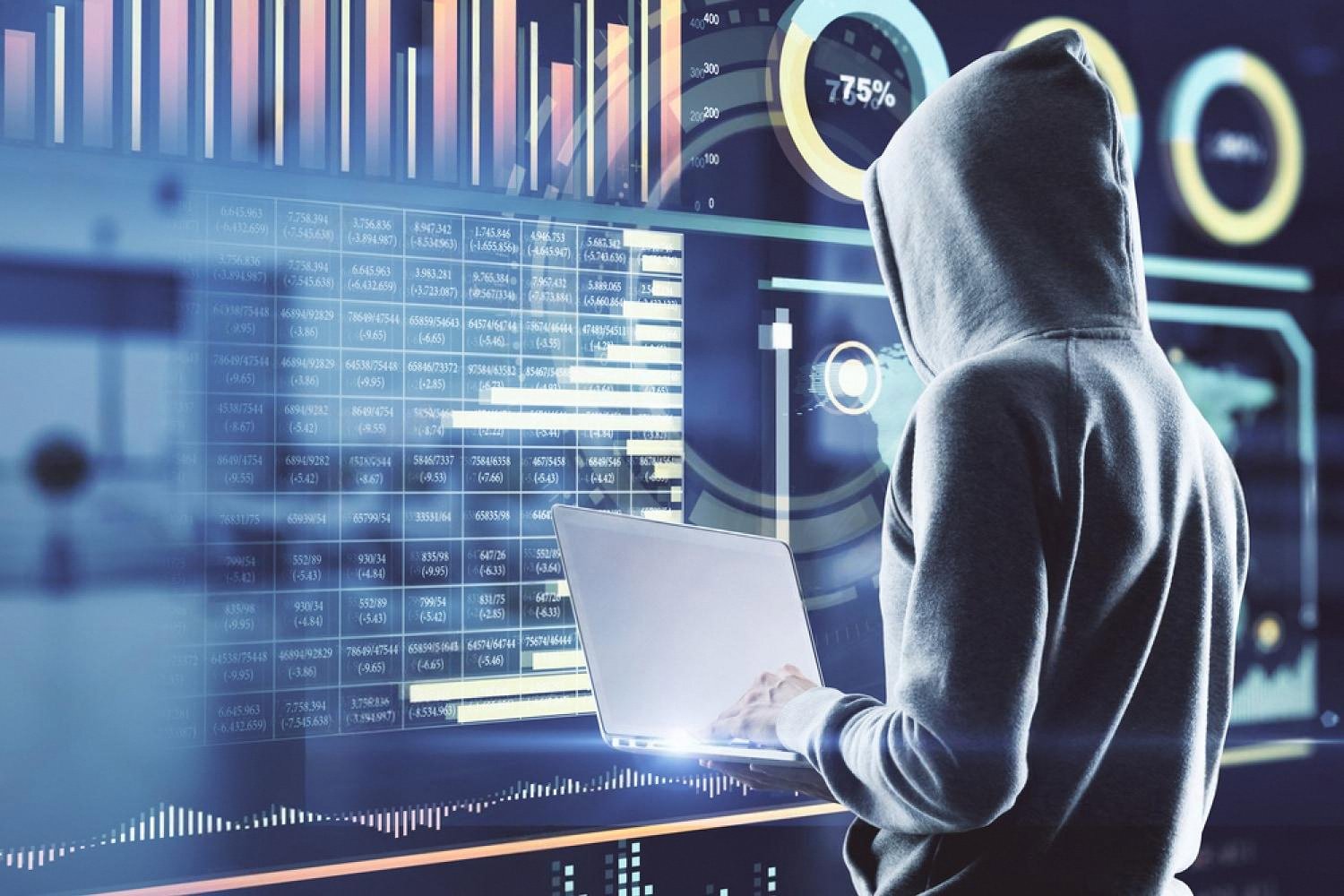 Person in a hoodie reviewing financial dashboards on a laptop, illustrating insider information leaks